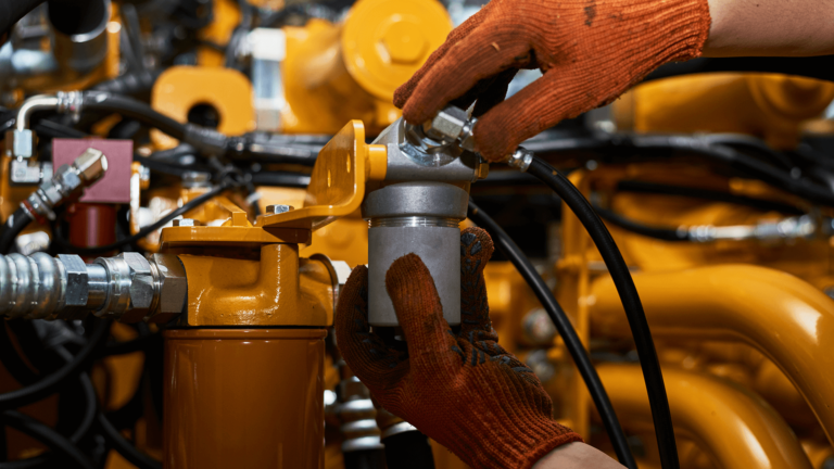 mechanic in orange gloves replacing hydraulics pipe